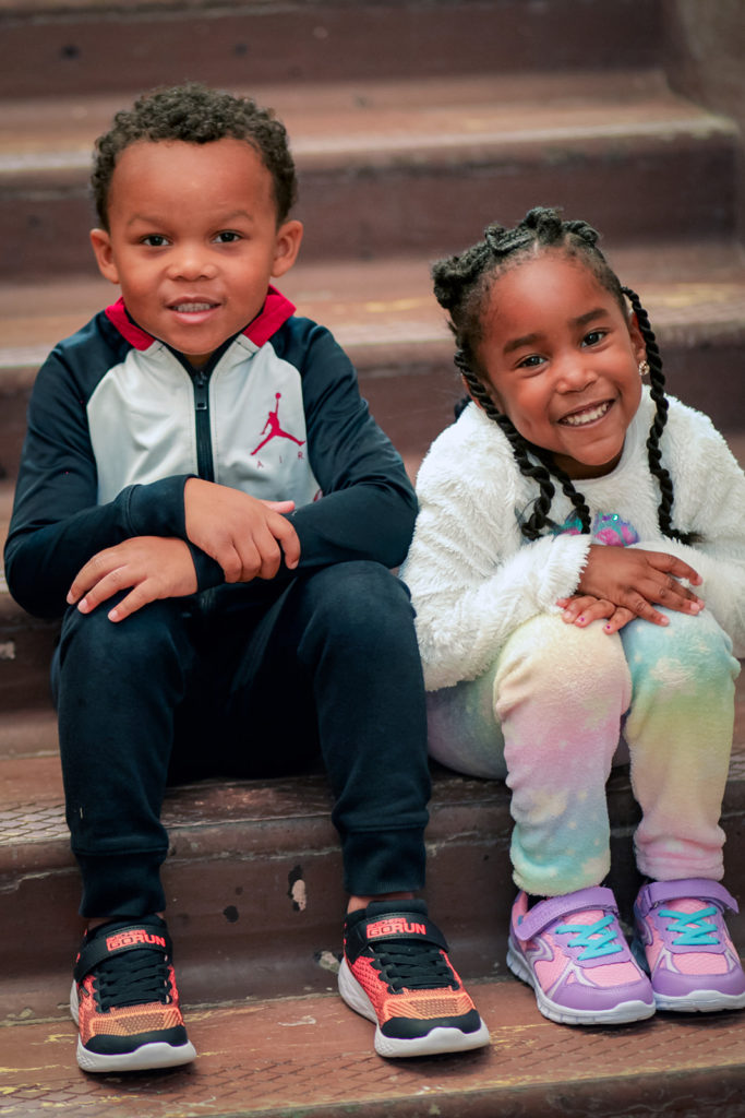 Two children sitting on steps wearing brand new tennis shoes.